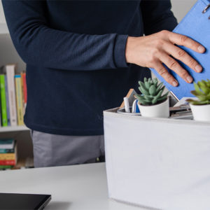 Mann packt persönliche Arbeitsmittel in Umzugsbox