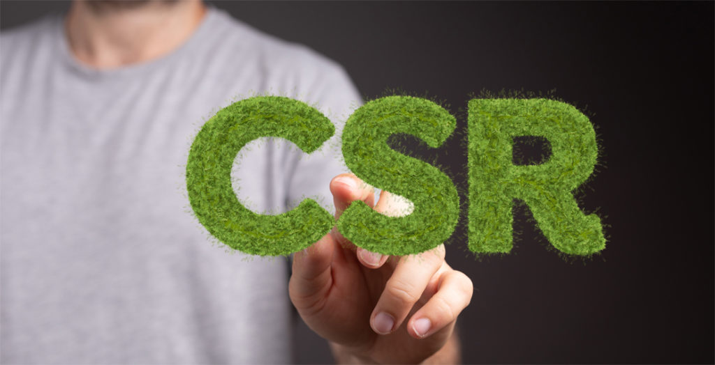 Hand zeigt auf Schriftzug CSR, gebildet aus Rasenfläche