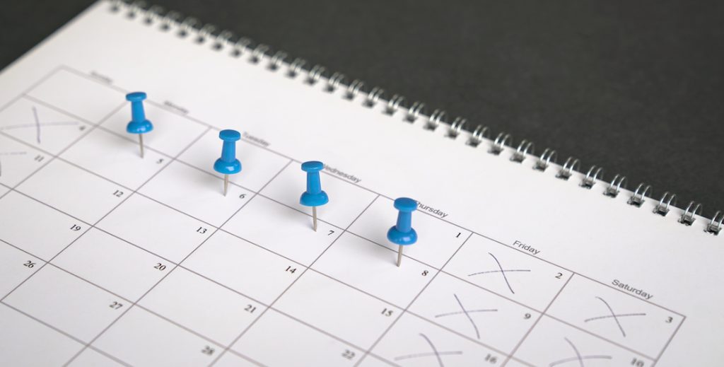 Vier Pinnadeln stecken auf einem Kalender