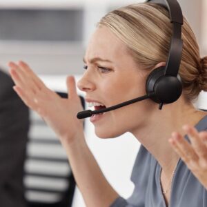 Call-Center-Mitarbeiterin frustriert am Telefon mit Headset